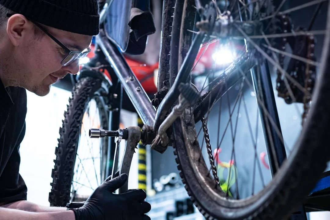 A cyclist's hands using a torque wrench on a carbon stem in a well-lit home workshop, with a SRAM groupset and premium tools laid out on a workbench